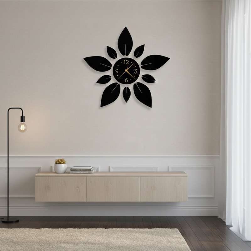 Decorative black wall clock with leaf design on a white wall.