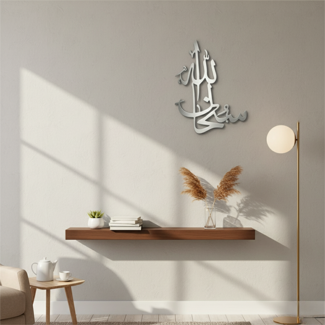 ArcDew SubhanAllah Calligraphy Art Islamic Acrylic Wall Decor UAE - arcdew.com - Silver acrylic ArcDew calligraphy art with Islamic design mounted on beige wall above wooden shelf and floor lamp.