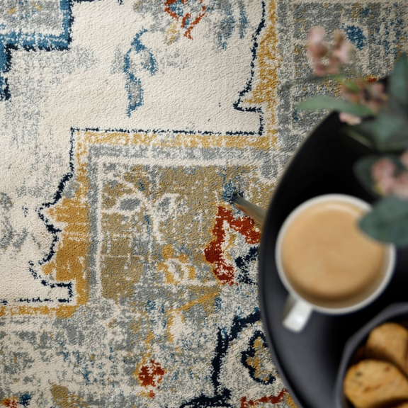 Colorful patterned rug with a cup of coffee and cookies on a table.