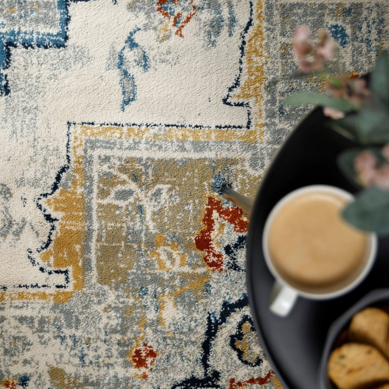 Colorful patterned rug with a cup of coffee and cookies on a table.