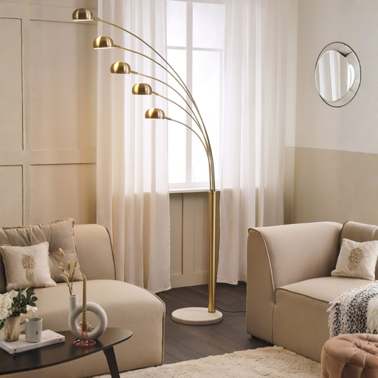 Modern living room with a gold arch floor lamp, beige sofa, and decorative items.
