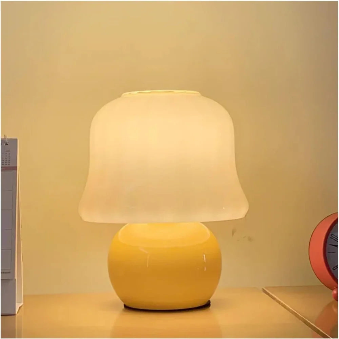 Yellow table lamp with a white shade on a wooden surface against a beige wall.