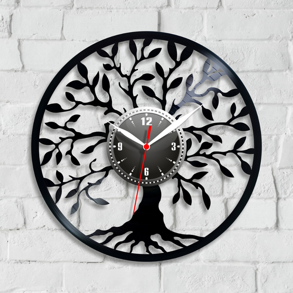 Decorative wall clock with tree design on a white brick wall