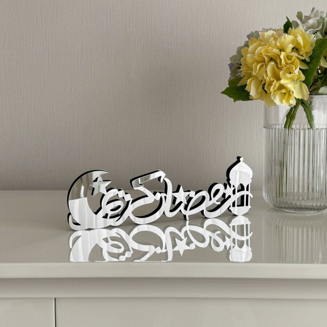 Decorative metal word sculpture spelling 'Euphoria' on a reflective surface with flowers in the background.